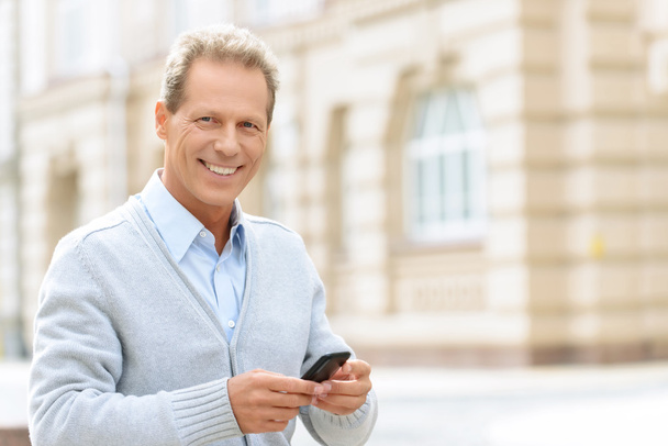 Smiling man holding mobile phone - Foto, Bild