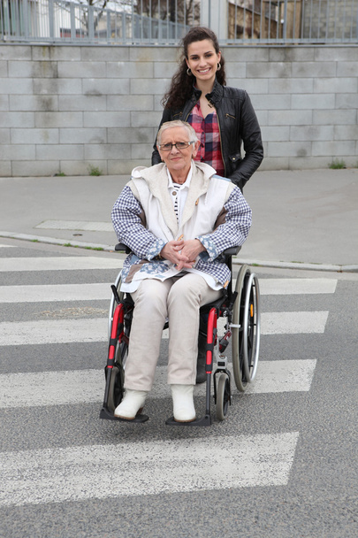 Girl pushing senior woman in wheelchair - Foto, Imagen