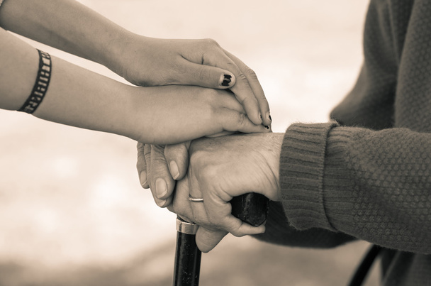 Closeup grandmother granddaughter holding hands, outdoors environment black and white edition - 写真・画像