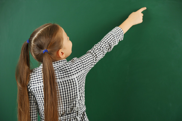 Beautiful little girl on blackboard background - Фото, изображение
