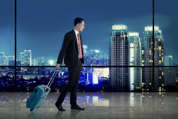 Business man walking with suitcase over city background - Φωτογραφία, εικόνα