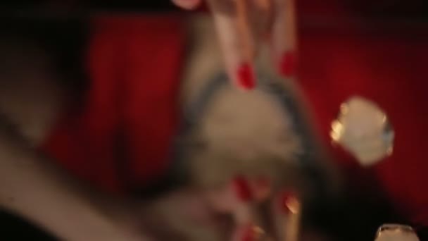 Hermosa morena en vestido rojo jugando con una vela y fusión de cubitos de hielo en la mesa del espejo
 - Imágenes, Vídeo