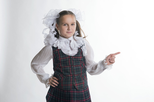 Schoolgirl with white bows in school uniform pointing to the whi - Foto, Imagem