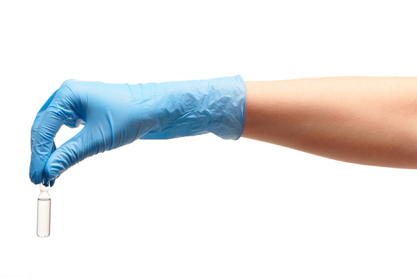 Close up van vrouwelijke arts hand in blauwe gesteriliseerde chirurgische handschoen bedrijf witte glazen ampul met een drug - Foto, afbeelding