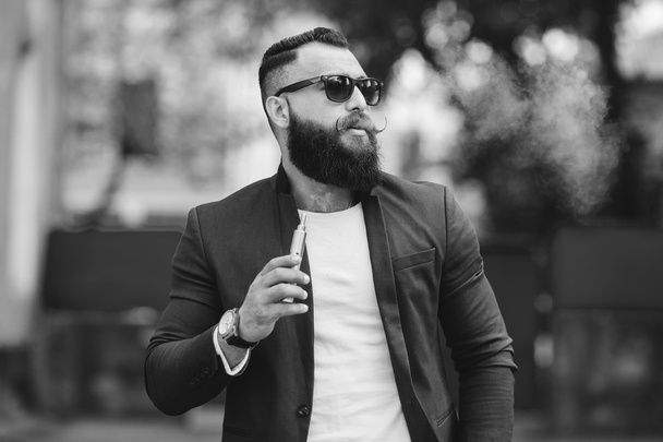 άνδρας με μούσι καπνίζει το ηλεκτρονικό τσιγάρο - Φωτογραφία, εικόνα