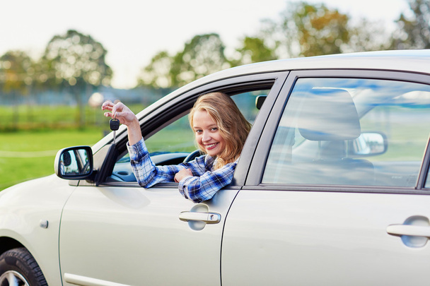 Krásný mladý řidič při pohledu z auta drží klíč - Fotografie, Obrázek