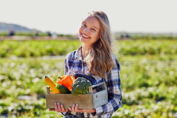 Młoda kobieta trzymając drewnianej skrzyni z warzywami - Zdjęcie, obraz