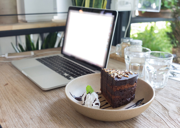 ahşap masa iş dizüstü dizüstü bilgisayar ile çikolatalı kek - Fotoğraf, Görsel