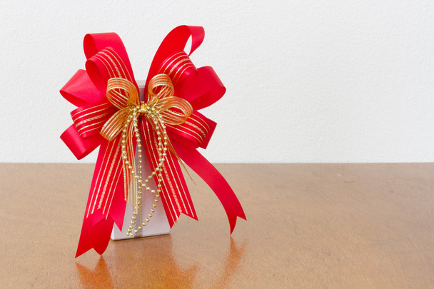 El gran arco rojo caja de regalo blanca en la madera
 - Foto, Imagen