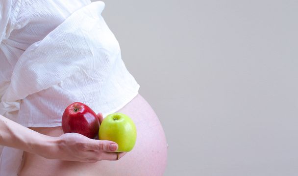 Een zwangere vrouw met appels in haar palm - Foto, afbeelding