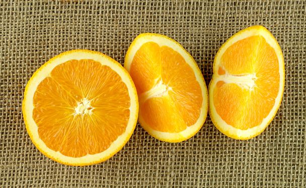 Нарезанные и нарезанные апельсины на фоне мешковины
 - Фото, изображение