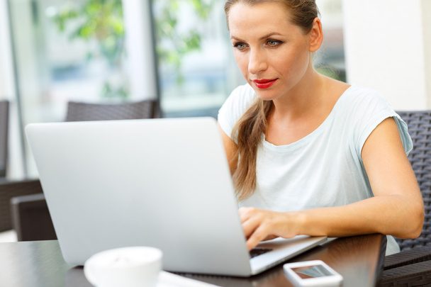 Młody biznes kobieta siedząc w kawiarni z laptopa i kawy - Zdjęcie, obraz