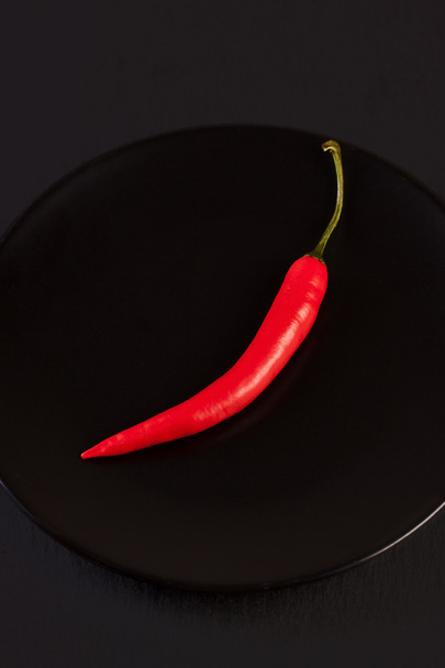 Πιπέρι κόκκινο σε μαύρο πλάκα σε μαύρο φόντο - Φωτογραφία, εικόνα