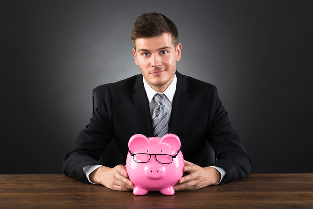 Businessman With Piggybank At Desk - Фото, изображение