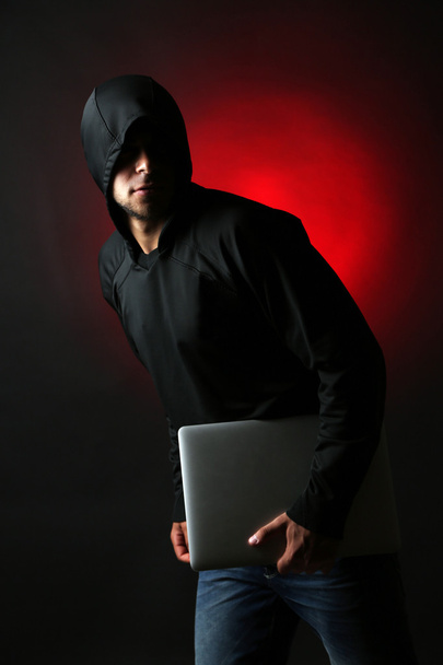 Hacker s počítačem a laptop na barevné tmavé pozadí - Fotografie, Obrázek