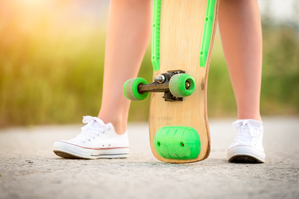 Anonymous teenage girl with skateboard, image with sunflare - Foto, imagen