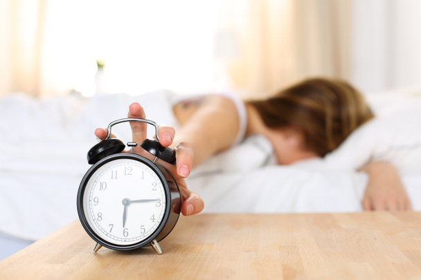 Sleepy young woman trying kill alarm clock - Photo, Image