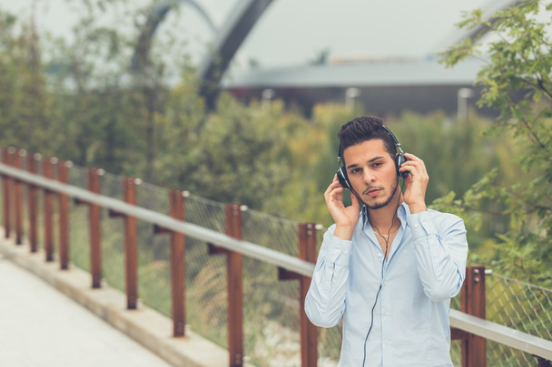 Joven hombre guapo escuchando música en un contexto urbano
 - Foto, Imagen