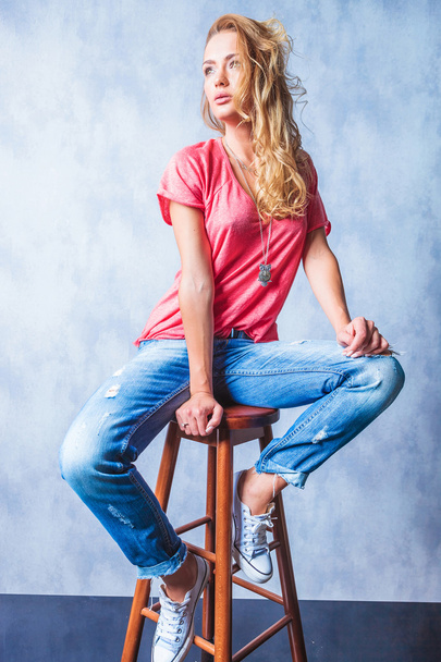 young blonde girl sitting on a chair looking away - Photo, Image