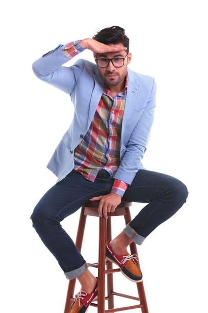 Young casual man sitting and looking at the camera - Photo, Image