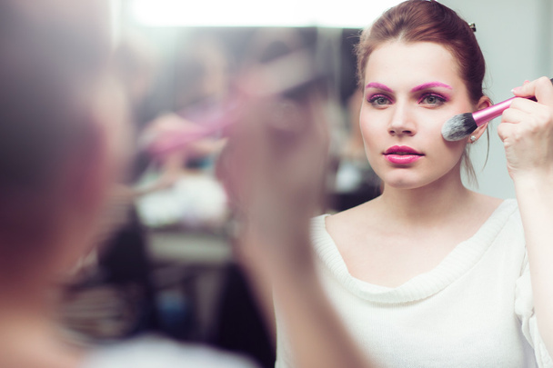 The girl with bright pink a make-up applies blush - Fotó, kép
