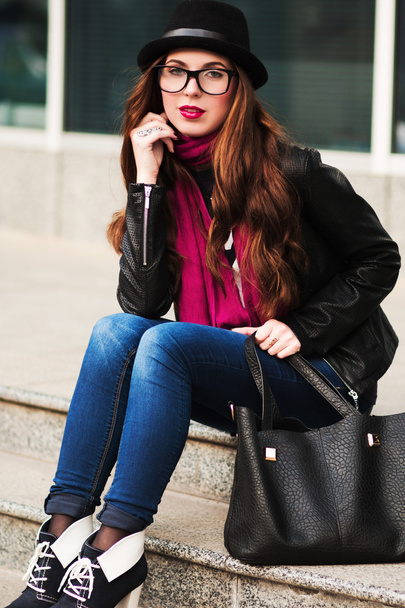 the stylish city girl in sunglasses  sits on steps - Foto, Imagem