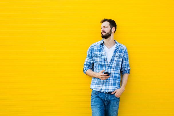 young handsome man with headphones on yellow wall - Foto, afbeelding