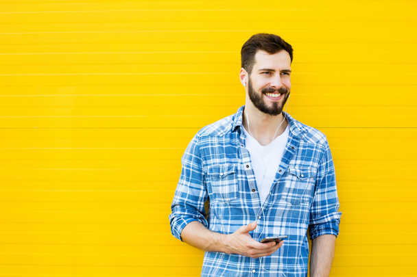 young handsome man with headphones on yellow wall - Φωτογραφία, εικόνα