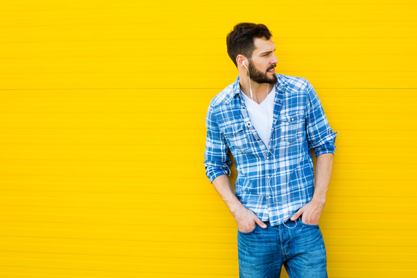 young handsome man with headphones on yellow wall - Photo, image