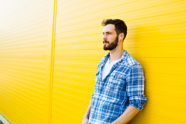 young handsome man with headphones on yellow wall - Fotó, kép