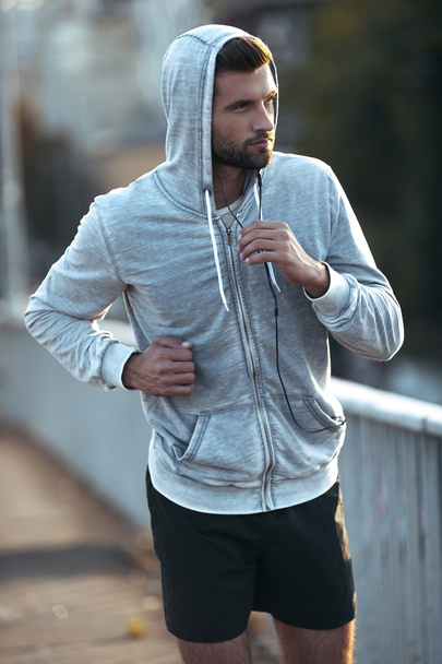 muscular man looking away while running along the road - Photo, Image
