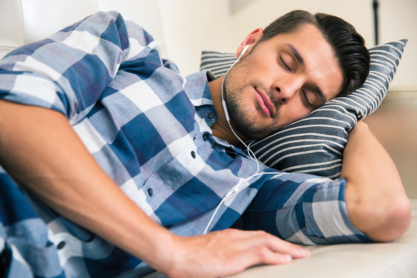 Man sleeping on the sofa with headphones at home - Zdjęcie, obraz