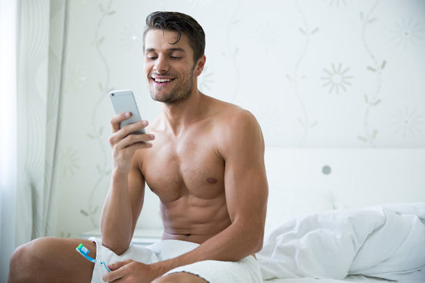 Man holding toothbrush and using smartphon - Foto, imagen