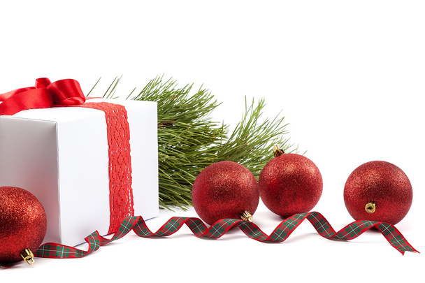 λευκό δώρου, με κόκκινο φιόγκο, Χριστούγεννα μπάλες γύρω από. - Φωτογραφία, εικόνα