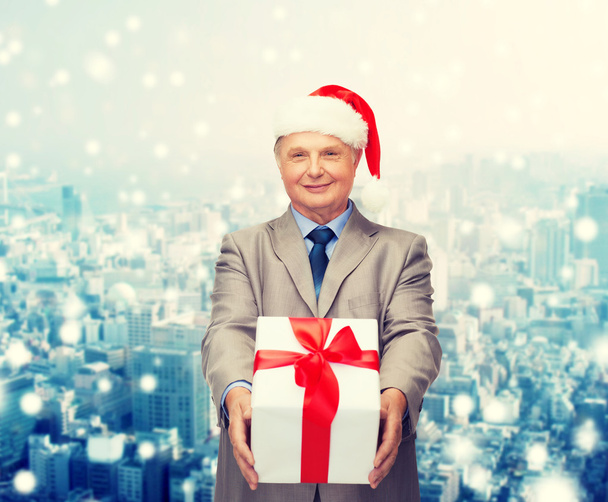 smiling man in suit and santa helper hat with gift - 写真・画像
