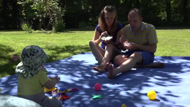 Gelukkig man en vrouw eten ijs op plaid en schattige baby blik bij hen. 4k - Video