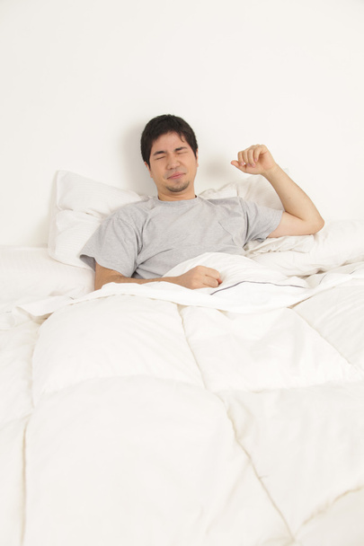 Homem que se estende em sua cama
 - Foto, Imagem