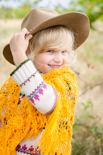 niña sonriente con sombrero y pelerina naranja en la temporada de otoño
 - Foto, Imagen