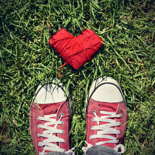 pies de hombre y bobina en forma de corazón de cuerda roja en la hierba, vignett
 - Foto, Imagen