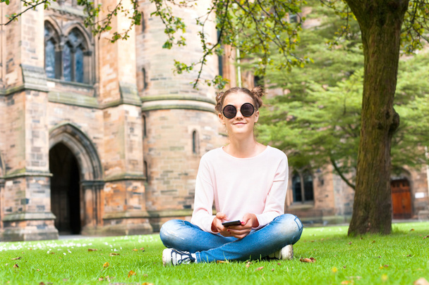 Panienka z telefon komórkowy siedząc w Glasgow University garde - Zdjęcie, obraz