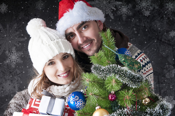 Young happy couple with gift boxes near the Christmas tree covering - Фото, зображення