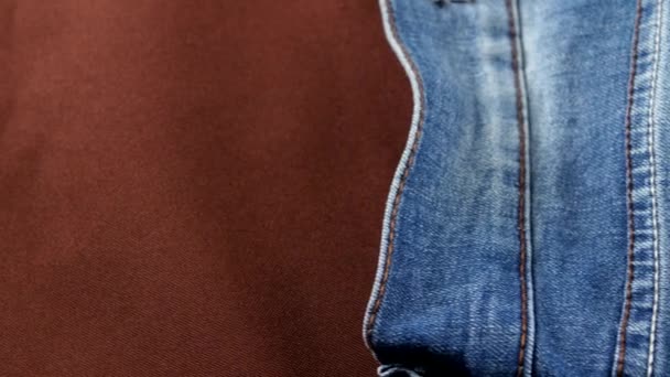 Blue jeans pocket on brown cloth, cam moves to the right, close up - Materiał filmowy, wideo