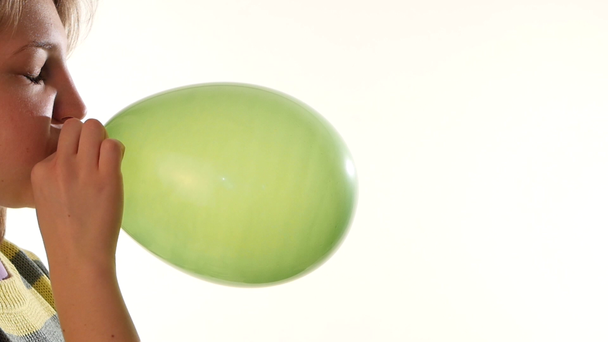 Kız beyaz arka plan, yavaş hareket izole yeşil bir balon üfleme - Video, Çekim