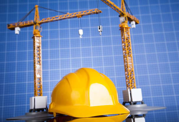 Plano de construção com guindaste e capacete amarelo
 - Foto, Imagem