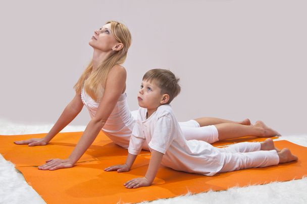 Uma bela jovem mãe pratica ioga com seu filho
 - Foto, Imagem