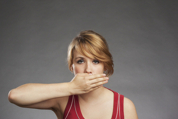 Teenage girl in red tank top covering eyes against gray background - Foto, Imagem