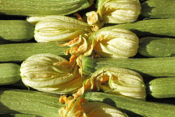 gestapelde courgette met bloemen op de Italiaanse markt - Foto, afbeelding