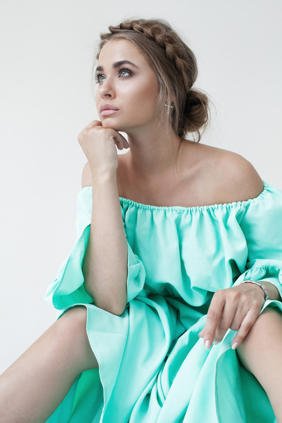 Portrait of beautiful woman with makeup and hairstyle in a turquoise dress - 写真・画像