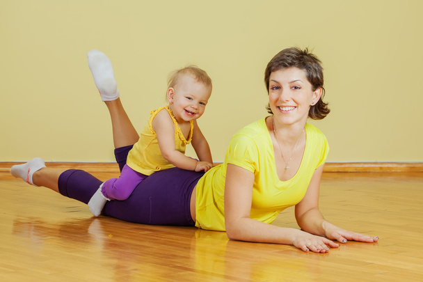 Mother does physical exercises with her daughter at home - Φωτογραφία, εικόνα