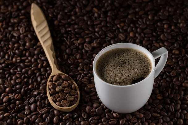 Cup of brewed coffee and French wooden spoon on a background beans - 写真・画像